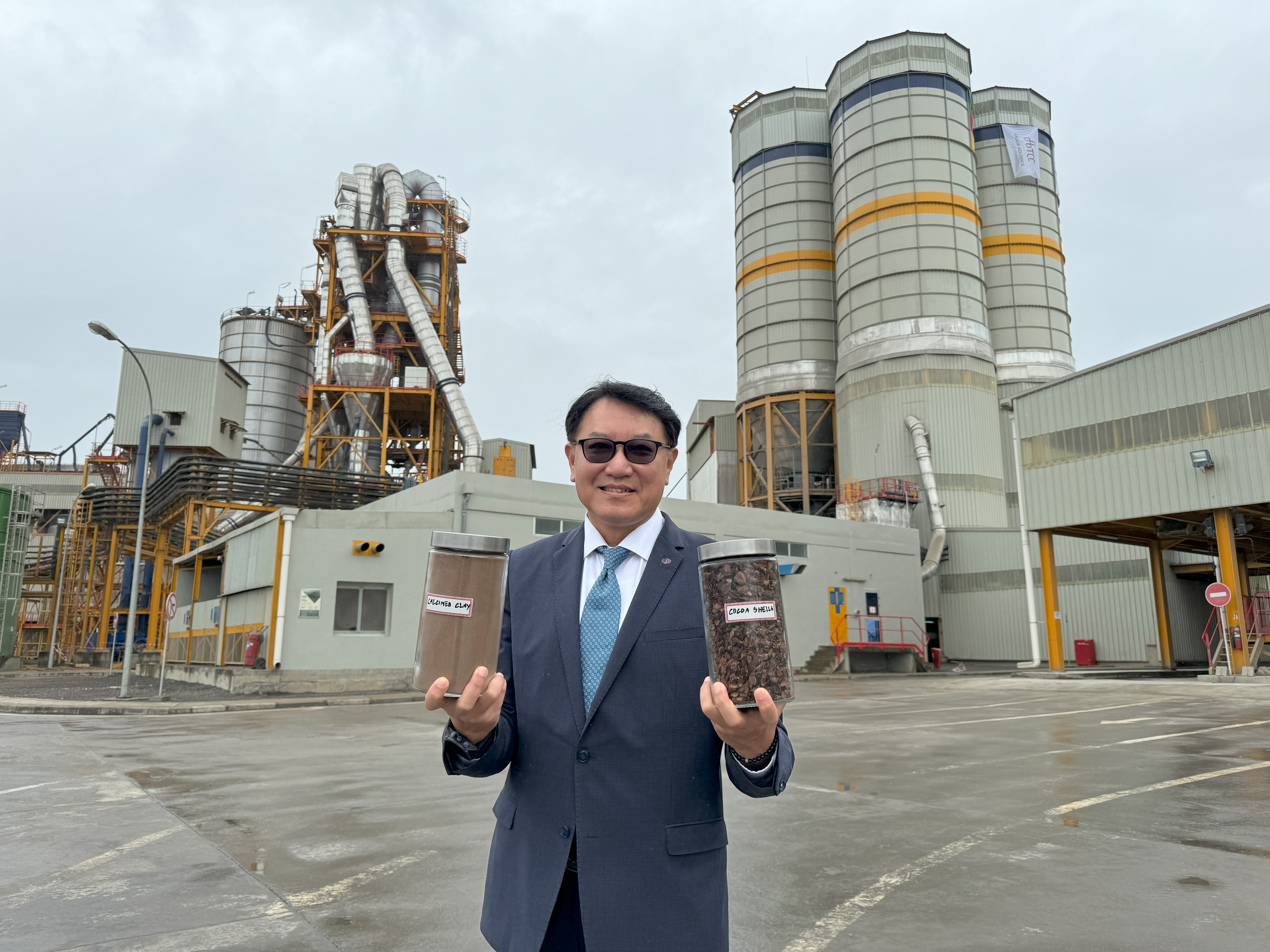 台 泥 總 經 理 程 耀 輝 親 赴 非 洲 喀 麥 隆 新 廠 , 並 展 示 了 ( 左 ) 低 碳 鍛 燒 黏 土 , ( 右 ) 可 作 為 生 質 燃 料 的 可 可 果 殼 。 台 泥 總 經 理 程 耀 輝 親 赴 非 洲 喀 麥 隆 新 廠 , 並 展 示 了 ( 左 ) 低 碳 鍛 燒 黏 土 , ( 右 ) 可 作 為 生 質 燃 料 的 可 可 果 殼 。