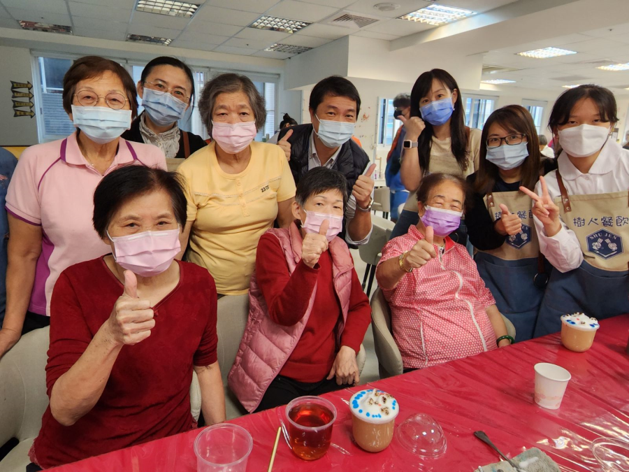 新北市樹人家商校長利政南（後排中）與餐飲管理科師生陪同長者體驗「可愛立體雕花茶飲」，提升新北社區銀髮服務量能。